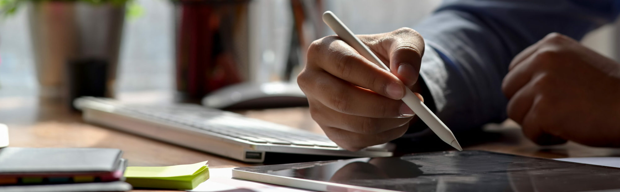 Close up view of graphic designer drawing on digital tablet with stylus and designer supplies on wooden worktable. DIY Graphic Design.